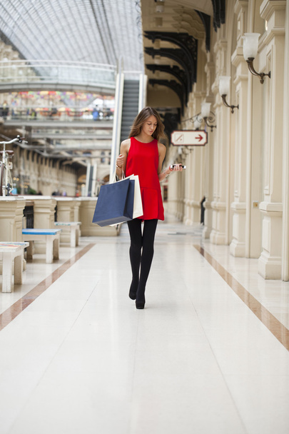 Молода жінка в червоній сукні ходить в магазині
  - Фото, зображення