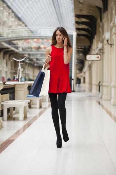 Beautiful young woman holding shopping bags walking in the shop - 写真・画像
