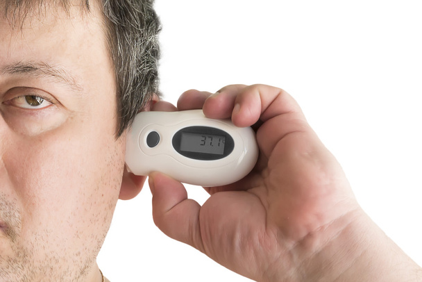the man takes temperature in an ear an infrared thermometer - 写真・画像
