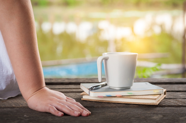 Xícara de café com notebook sobre mesa de madeira rústica
 - Foto, Imagem