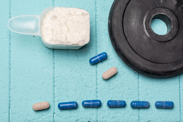 Container of milk whey protein and pills. Close-up. Blue background - Photo, Image