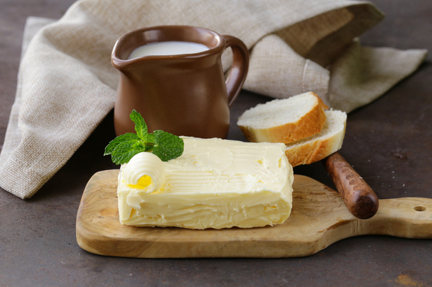 bloco de manteiga orgânica fresca em uma tábua de madeira
 - Foto, Imagem