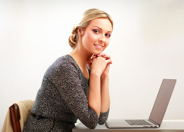 A portrait of a businesswoman sitting at a desk with a laptop - Fotoğraf, Görsel