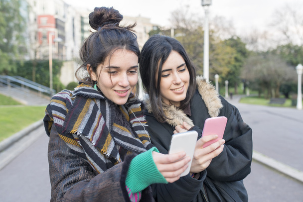 Zwei Hipster beglücken Freundinnen mit Smartphone. - Foto, Bild