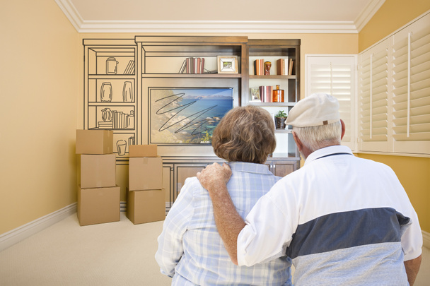 Senior Couple Looking At Drawing of Entertainment Unit In Room - Photo, Image