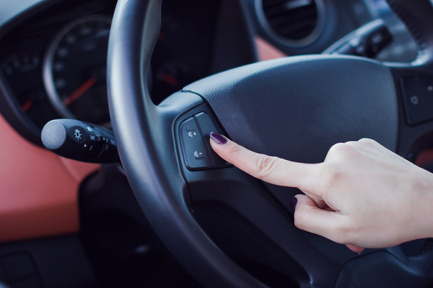 Woman hands push the button on a steering wheel in car - Foto, imagen