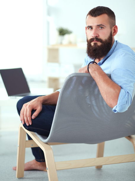 Young businessman sitting on chair in office - Фото, зображення