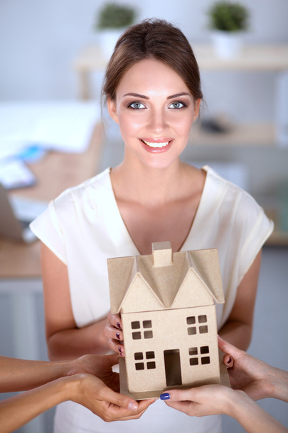 Portrait of female architect holding a little house, standing in office - Foto, Imagem