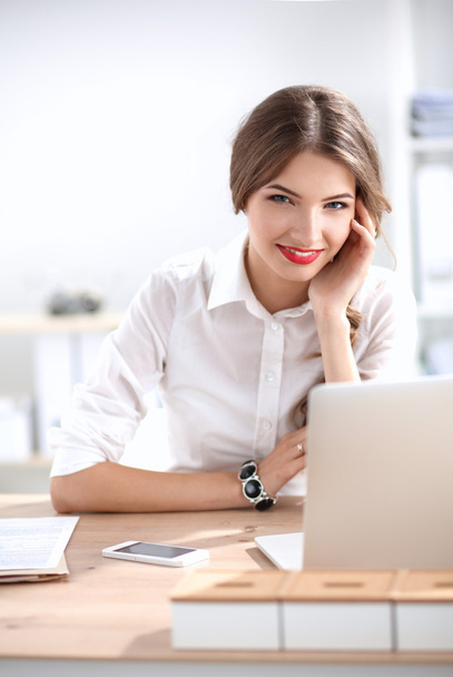 Attractive businesswoman sitting  on desk in the office - Zdjęcie, obraz