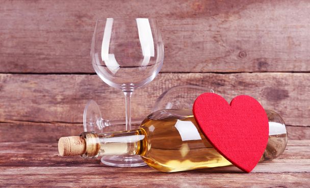 Red heart with wine bottle and glasses on wooden background - Valokuva, kuva