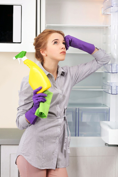 Молода жінка прибирає порожній холодильник з губкою
 - Фото, зображення