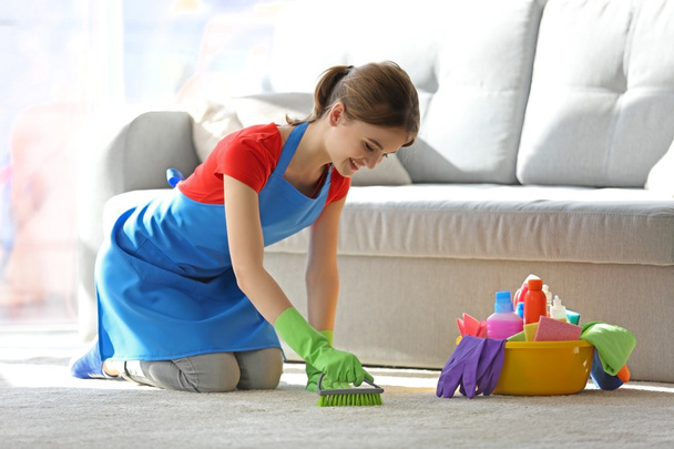 Mujer joven limpia la alfombra en la habitación
 - Foto, Imagen