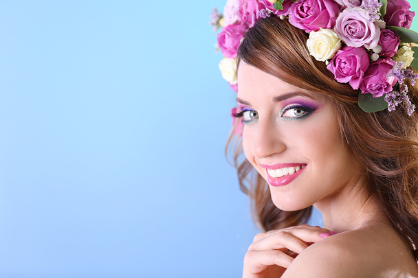 Beautiful young woman wearing floral headband on a blue background - Photo, image