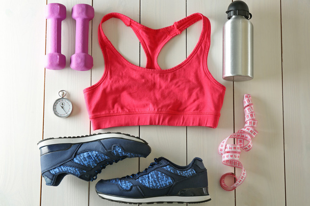 Athlete's set with female clothing, equipment and bottle of water on white wooden background - Photo, Image