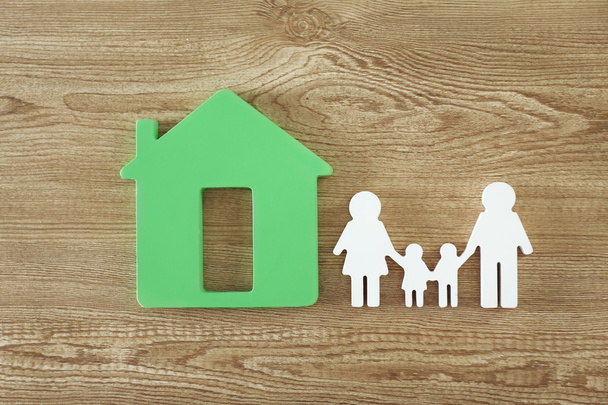 Family figure with a house on wooden  background - Photo, image