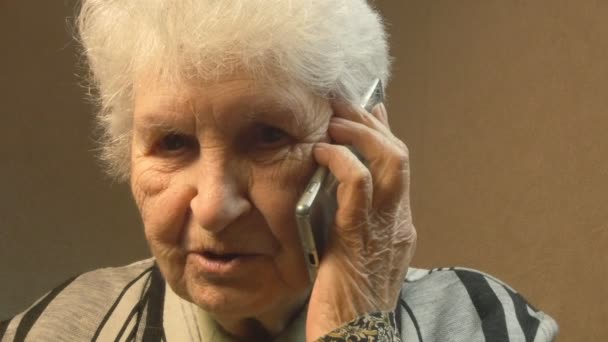 Vanha nainen puhuu puhelimessa.
 - Materiaali, video