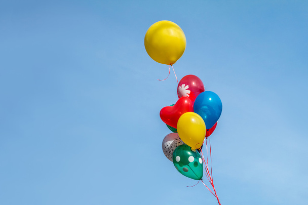 Барвиста повітряна куля плаває в повітрі на тлі яскравого блакитного неба
. - Фото, зображення