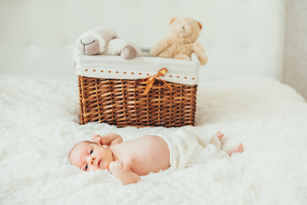 pequeño bebé (bebé) acostado en una manta cerca de la canasta con arena
 - Foto, imagen