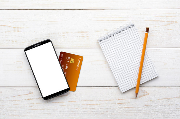 Smartphone, notebook, potlood en creditcard op een witte tafel - Foto, afbeelding