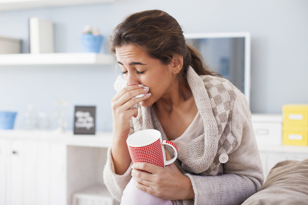 sick woman blowing nose and drinking tea - Foto, afbeelding
