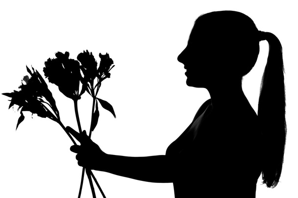 Young woman silhouette giving flowers - 写真・画像