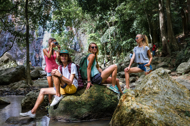 Young tourists are resting on the rocks in the jungle waterfall in the background - Foto, Imagem