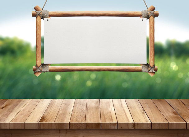Wood table with hanging wooden sign on green nature blurred background - Фото, изображение