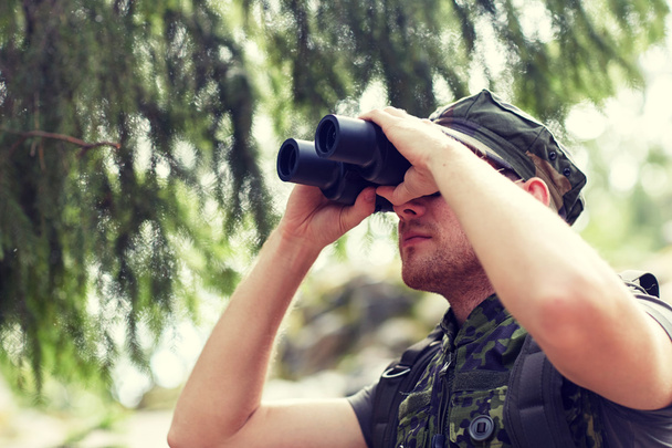 young soldier or hunter with binocular in forest - Photo, image