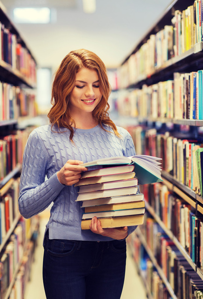 happy student girl or woman with books in library - Photo, Image