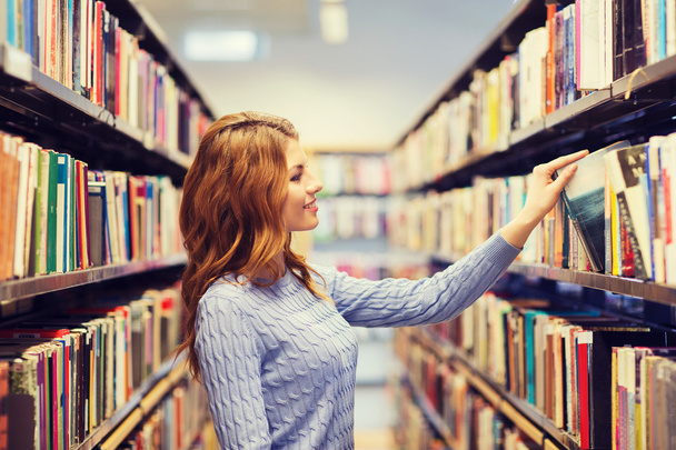 happy student girl or woman with book in library - Фото, изображение