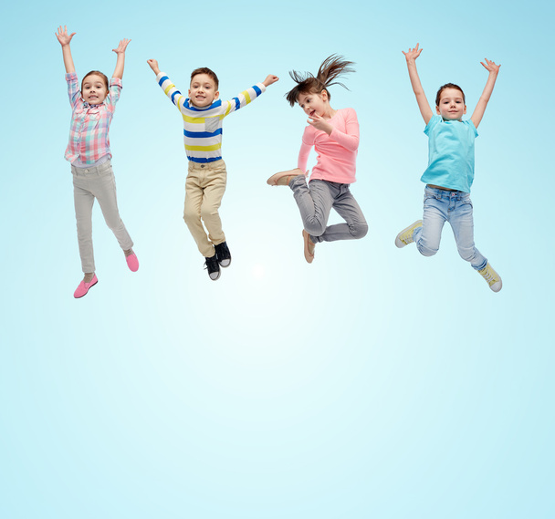 happy little children jumping in air over blue - 写真・画像
