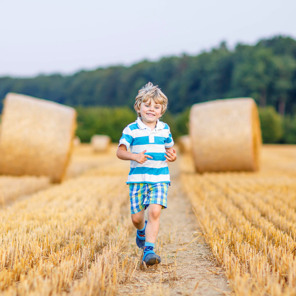 Kis gyerek fiú játszik a széna mező, szabadban - Fotó, kép