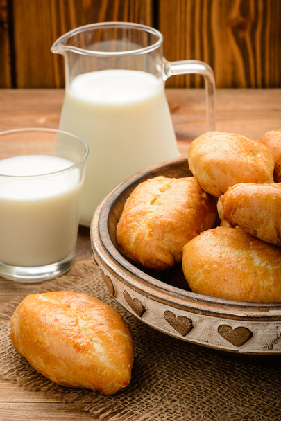 Traditional  russian pastry piroshki and milk on wooden table. - Photo, Image
