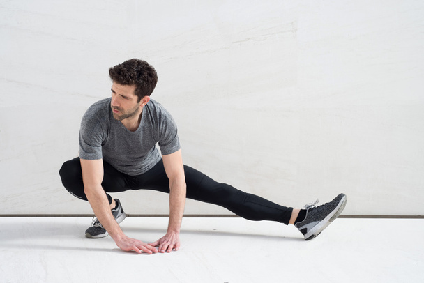 man stretches leg in the ground marble - Fotó, kép