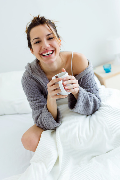 Beautiful young woman drinking coffee on bed. - Foto, Bild