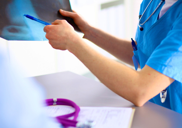 врач со стетоскопом на приеме пациентов за столом
 - Фото, изображение