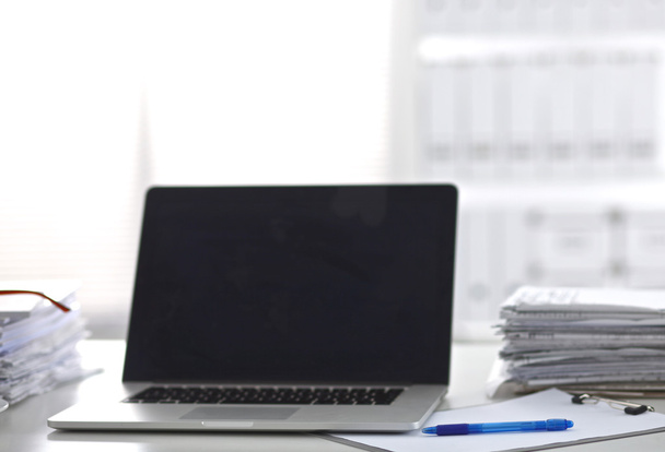 Laptop z stosem folderów na stole na białym tle - Zdjęcie, obraz