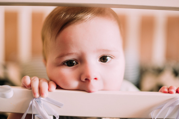 Retrato de cerca de un lindo bebé alegre en la cuna en casa
 - Foto, Imagen