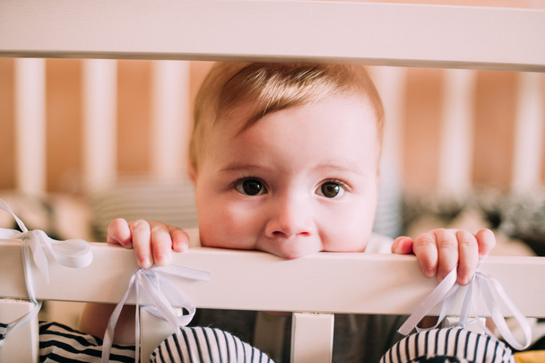 Close-up portret van een vrolijke, schattige baby in de wieg thuis - Foto, afbeelding