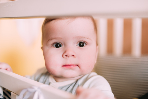 Close-up portret van een vrolijke, schattige baby in de wieg thuis - Foto, afbeelding