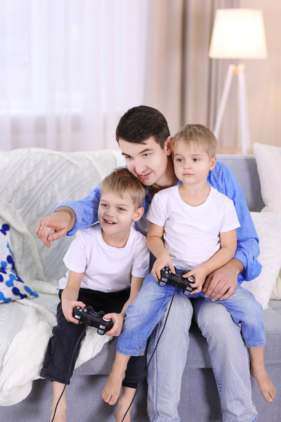 Family concept. Father with sons are playing video games in the room - Fotó, kép