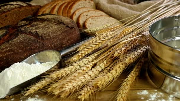 Chléb, snop pšenice uši a mouky na dřevěný stůl, dolly, pohled shora - Záběry, video
