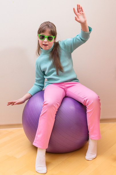 Young little girl sitting on big ball - Foto, imagen