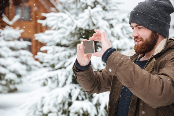 Man taking pictures with mobile phone in winter - 写真・画像