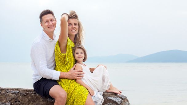 Jovem família está sentada na parede no fundo do mar tropical
 - Foto, Imagem