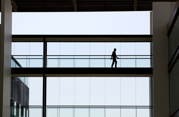 Вид силуэта молодого бизнесмена в современном интерьере офисного здания
 - Фото, изображение