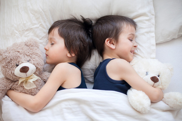 Two boys with teddy bears, lying in bed, sleeping in the afterno - Foto, immagini