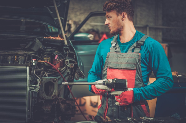 Mechaniker mit Druckluftwerkzeug in der Werkstatt - Foto, Bild