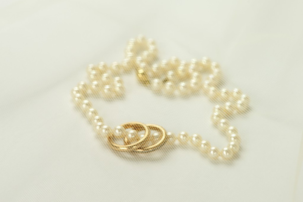Collar de perlas con dos anillos de oro
 - Foto, Imagen