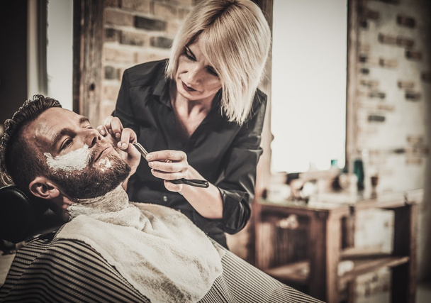Cliente durante el afeitado de barba en la peluquería - Foto, Imagen